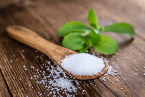 Learn-How-To-Make-Ice-Cream-Without-Added-Sugar-image-2-wooden-spoon-with-Stevia-granules-and-stevia-plant-leaves-Frosted-Fusions